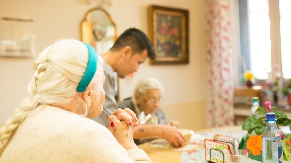 Pfleger mit Seniorinnen im Gemeinschaftsraum