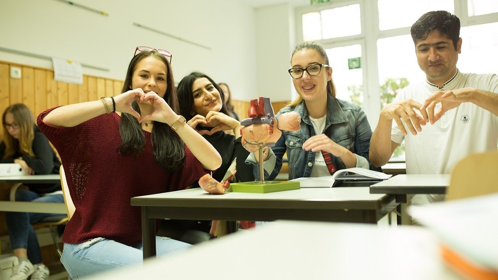 Schüler im Klassenzimmer formen mit ihren Händen Herzen